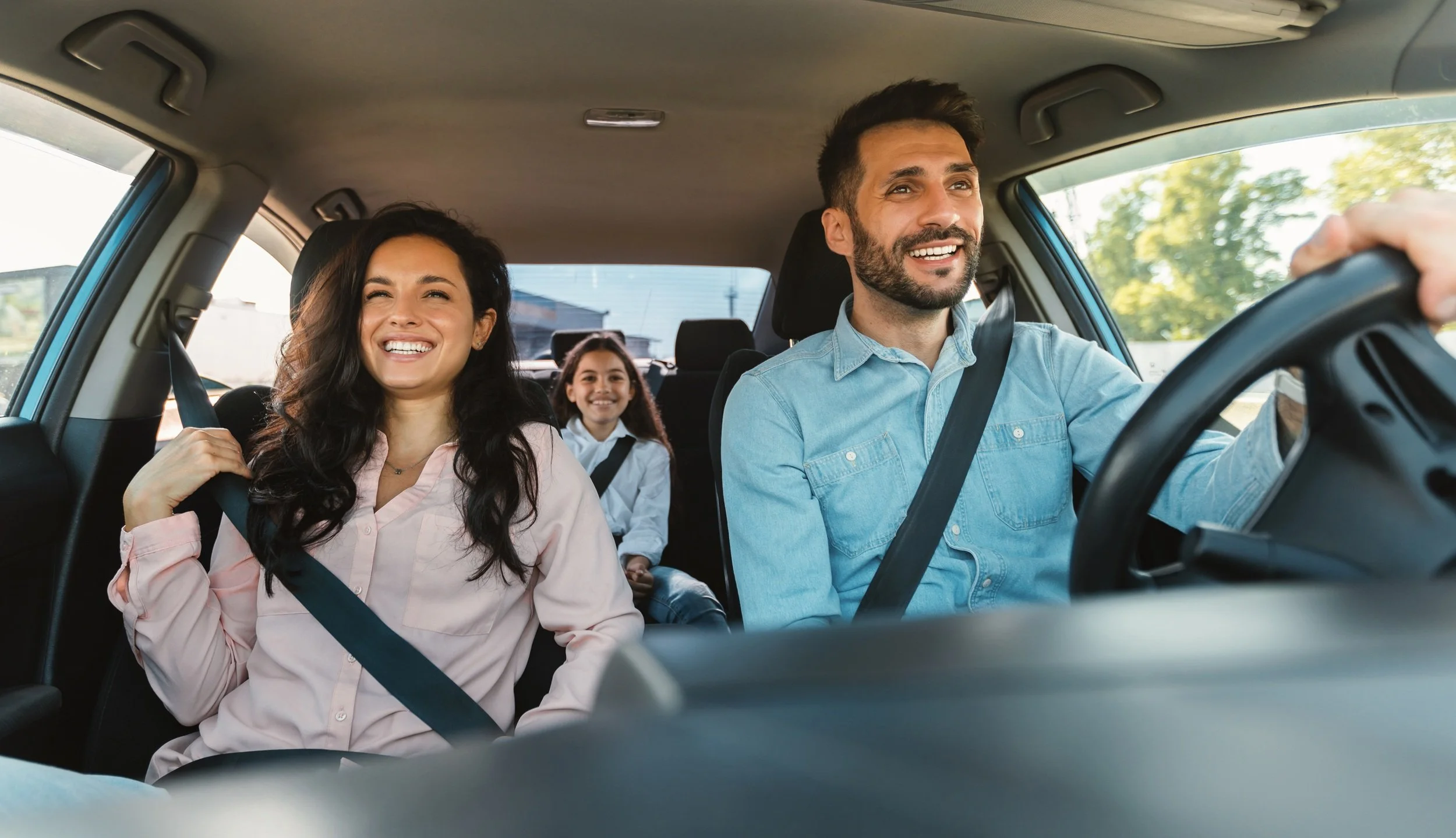 Happy family of three riding car, traveling by automobile together, parents and daughter enjoying road trip