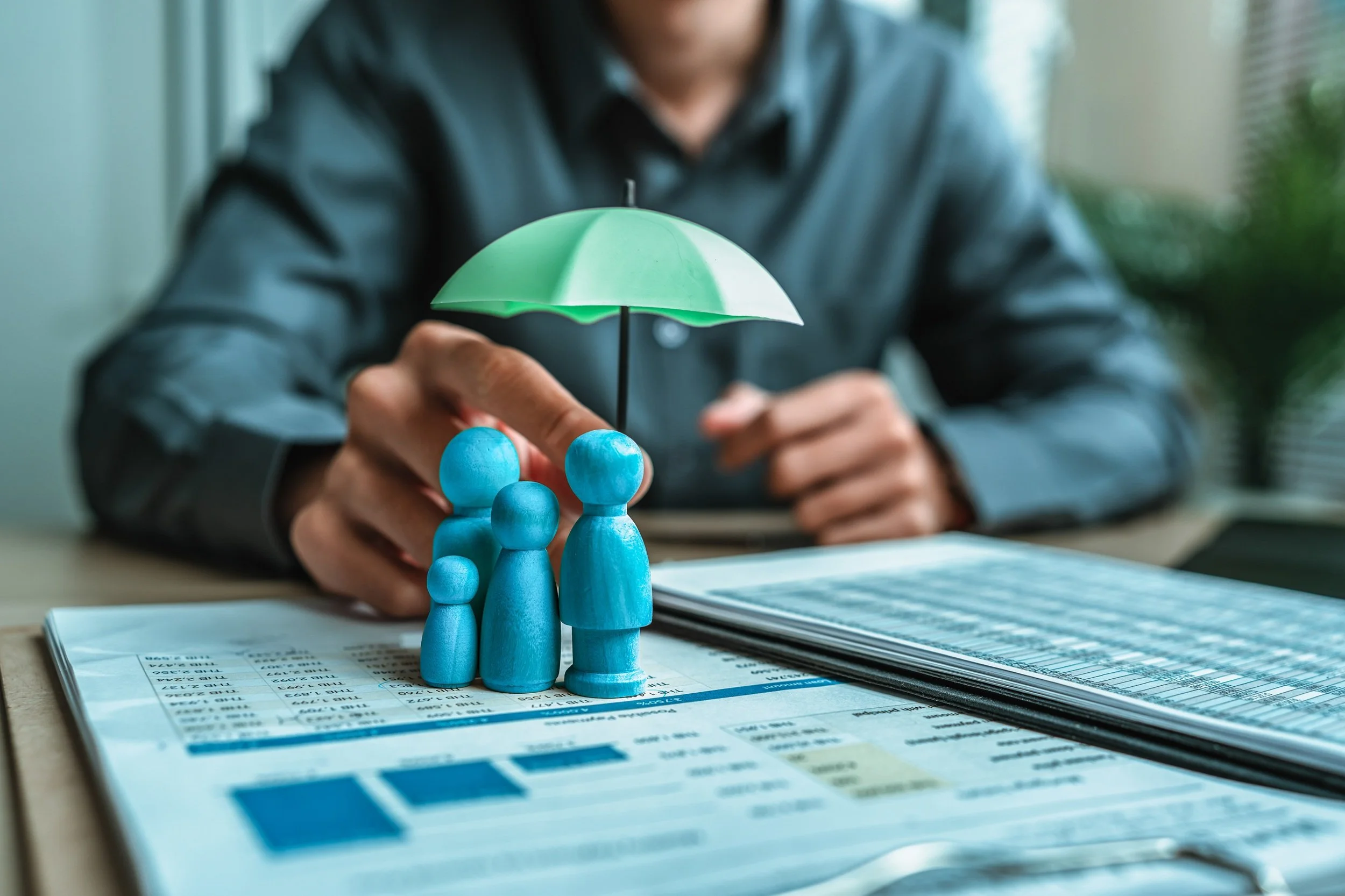 A wooden doll under an umbrella holding by broker representing insurance