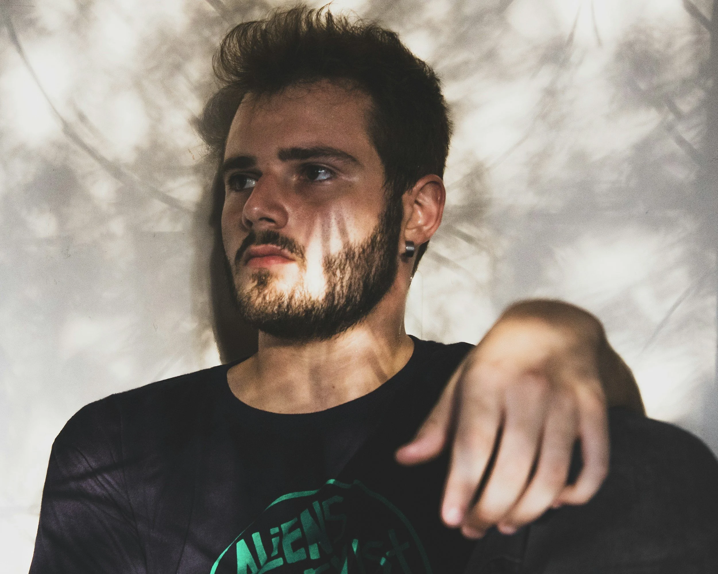 man sitting against a wall with sunlight coming through some trees onto his face