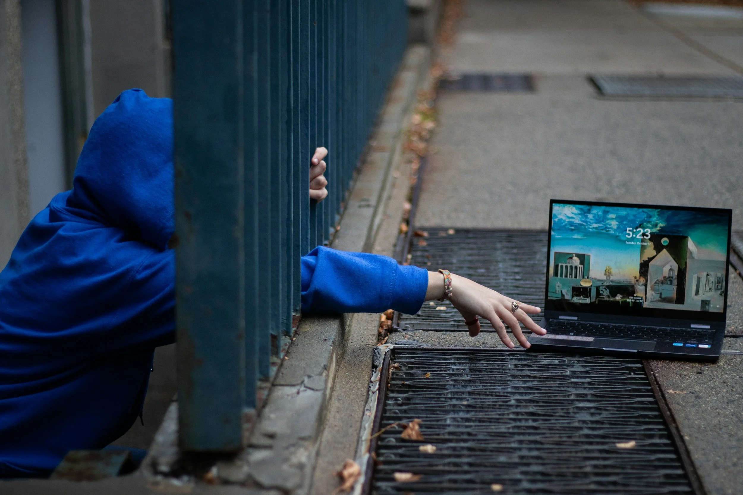 someone reaching through bars trying to get a laptop