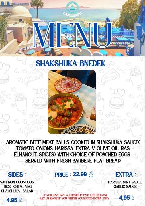 A restaurant menu featuring a seaside view with blue and white decor. It highlights a dish called Shakshuka Bnedek, which includes aromatic beef meatballs cooked in shakshuka sauce served with flatbread, and sides like saffron couscous, rice, chips, 