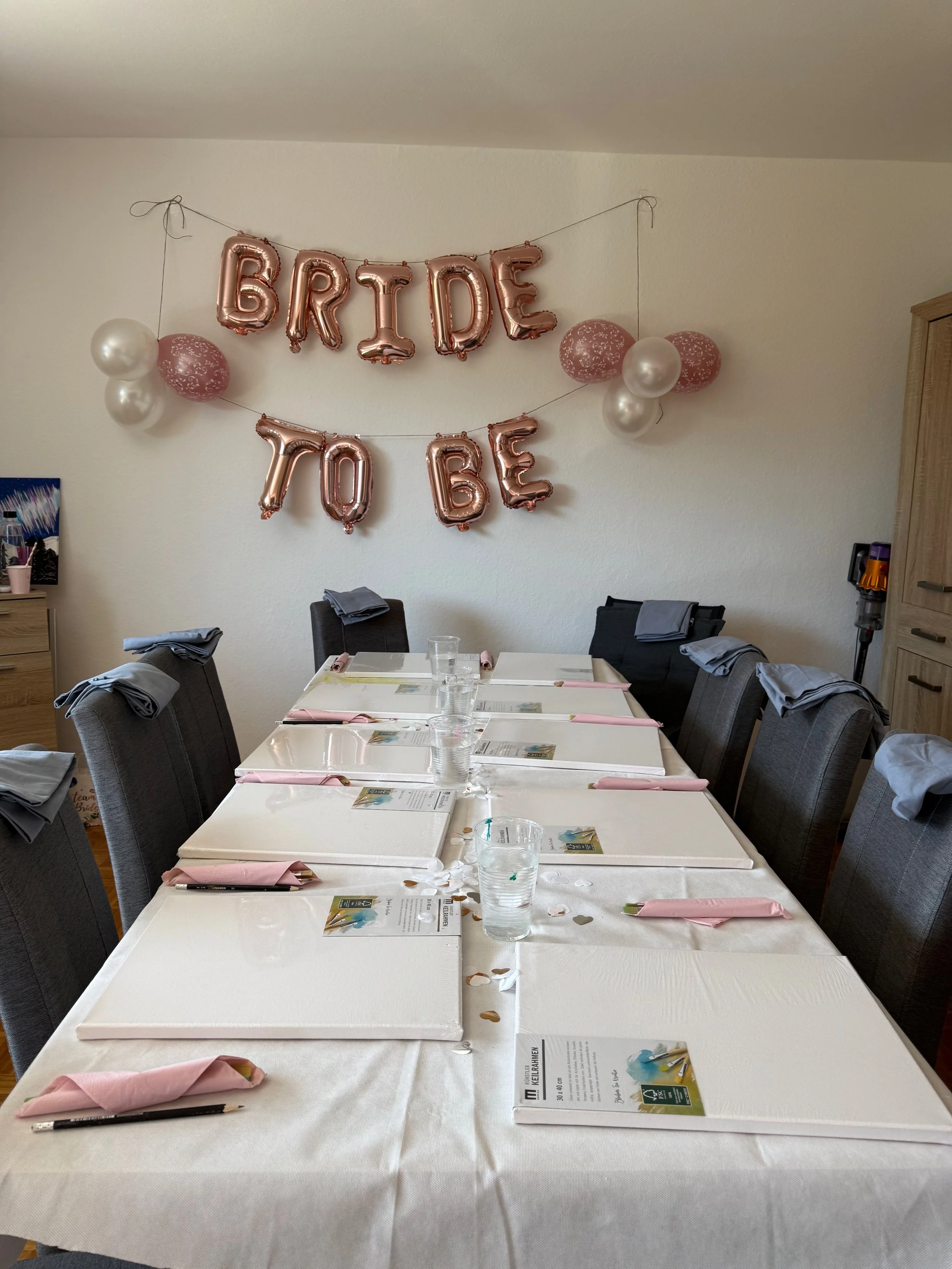 Ein festlich gedeckter Tisch für eine Feier, mit Ballons und einem Banner mit der Aufschrift "Bride to Be" an der Wand.