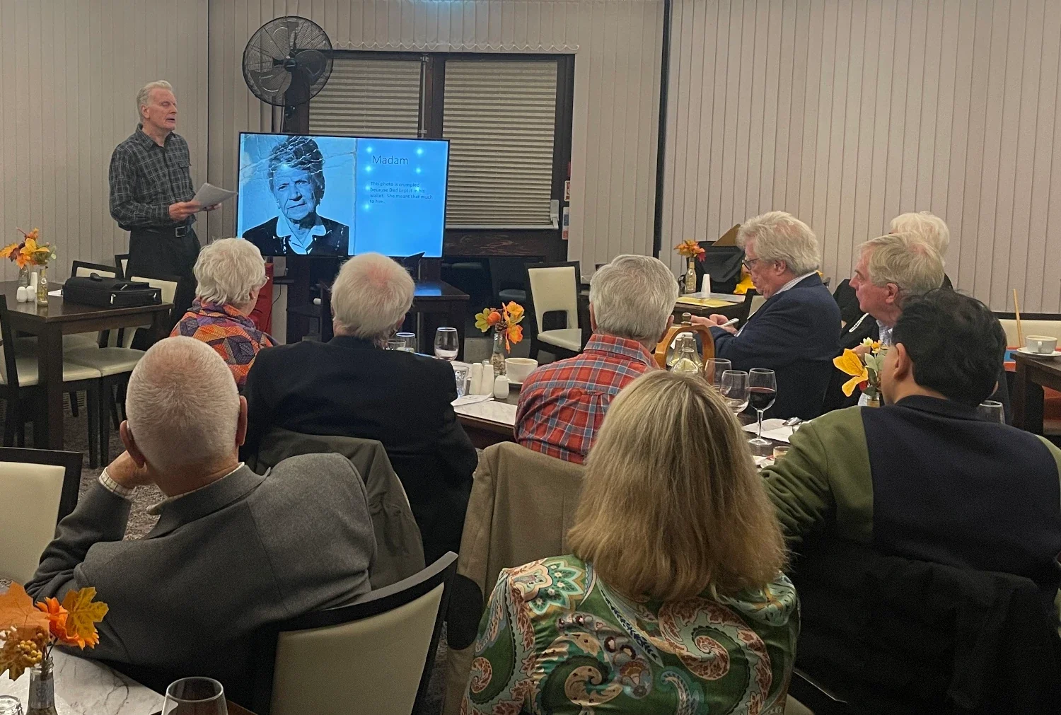 A group of Rotarians listening to a speaker at a Rotary meeting.