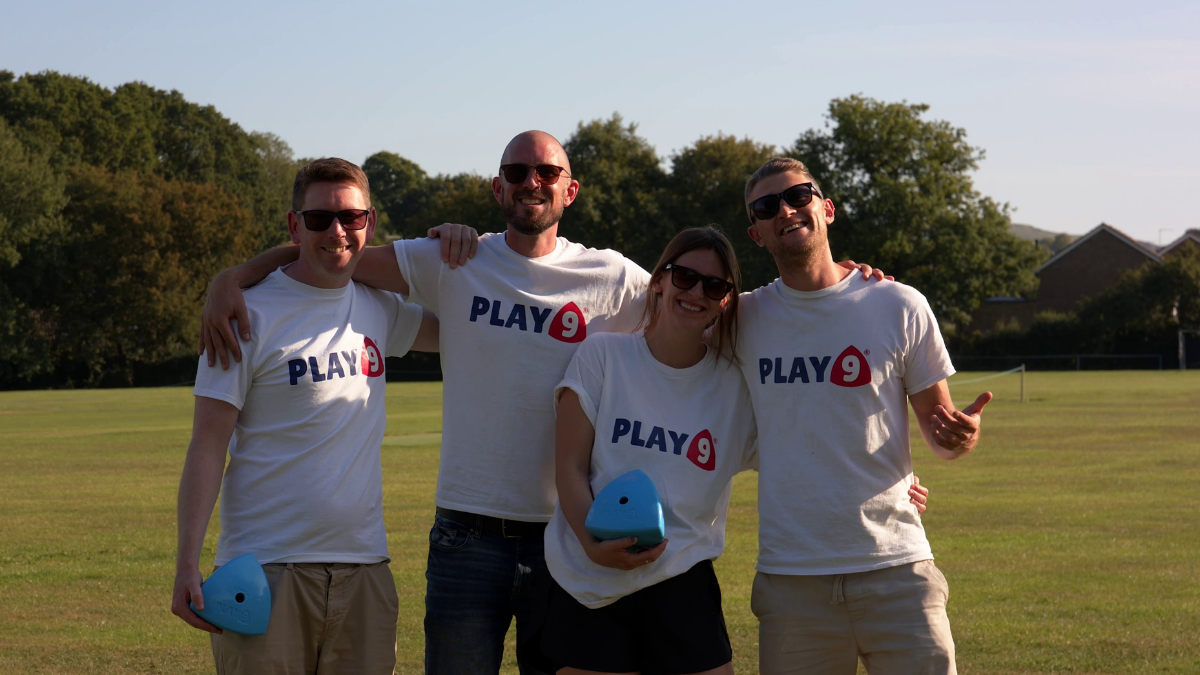 The play 9 team stand in a field smiling to camera wearing sunglasses and holding their dog toy product the roolo