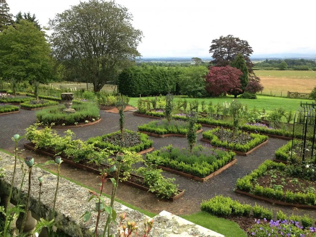 Formal parterre beds arranged before a view to open farmland and mature trees, Rowchester.