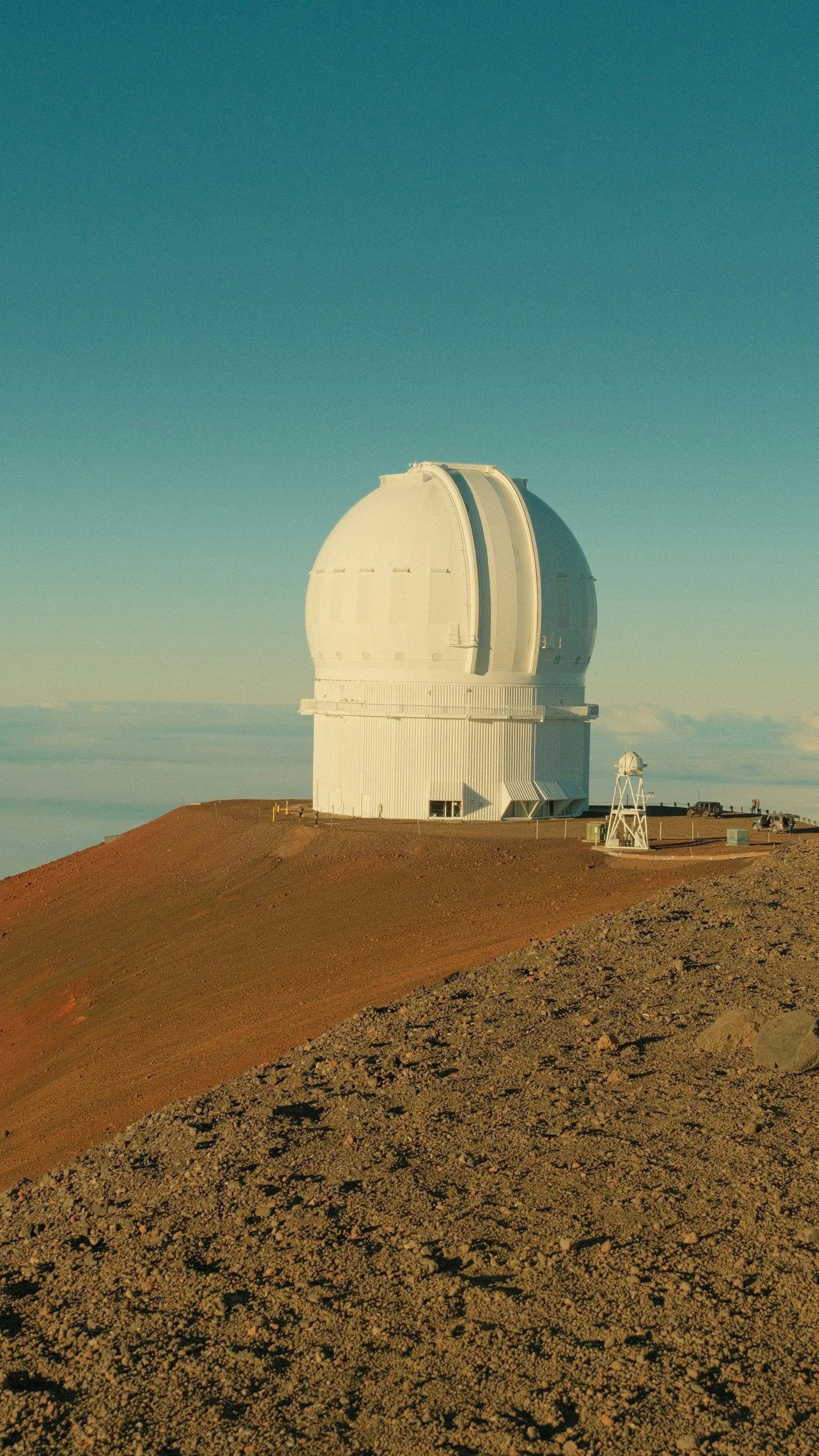 A large white observatory telescope dome on a mountain top with a clear sky in the background.