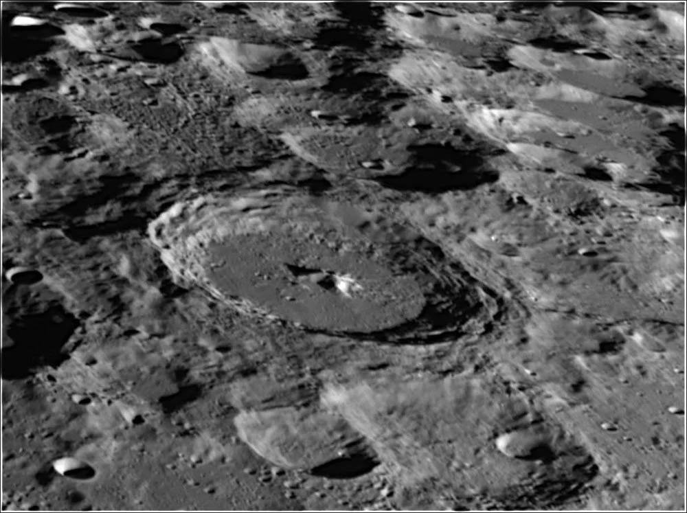 A black and white photograph of the moon's surface showing numerous craters and rough terrain.