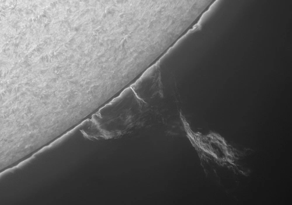 Close-up of the edge of a piece of paper or fabric showing frayed fibers and tearing.