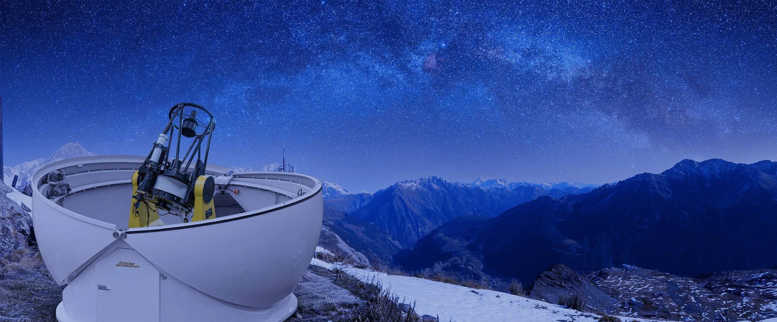 A large telescope and a telescope mount set up on a mountain overlooking a snowy landscape and snow-capped mountains under a starry night sky with the Milky Way galaxy visible.