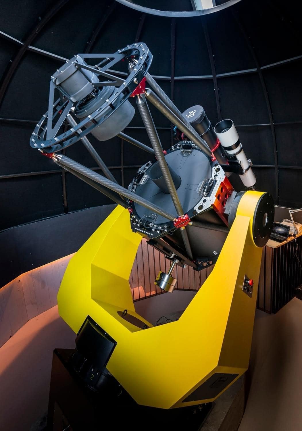 Large telescope with a yellow mount (AZ6000DDS by 10Micron) inside a dome observatory.