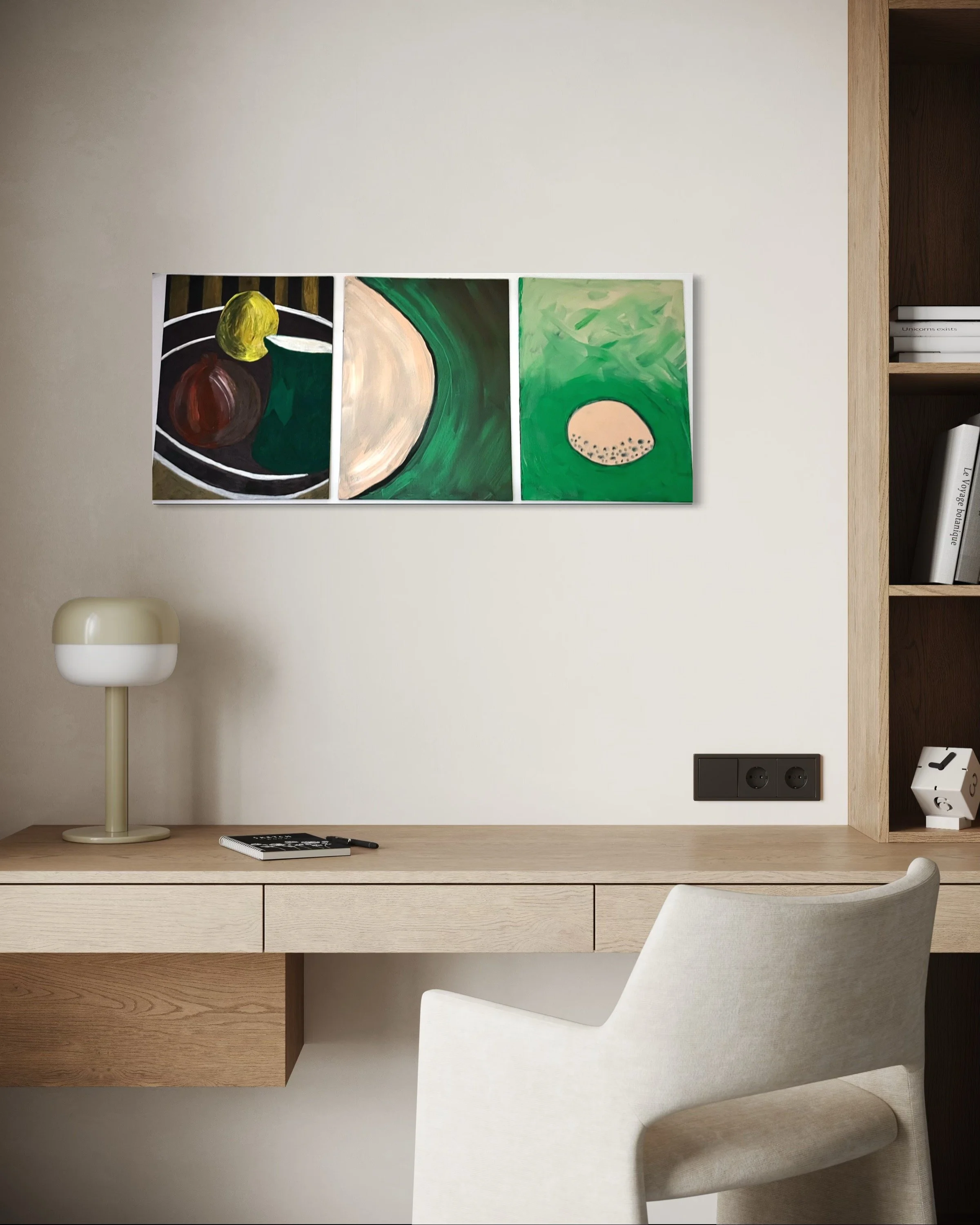 A modern workspace with a wooden desk, a white upholstered desk chair, a beige and white table lamp, a notebook with a pen, and an abstract triptych painting of three images with green, black, beige, and brown colors, hanging on a white wall.