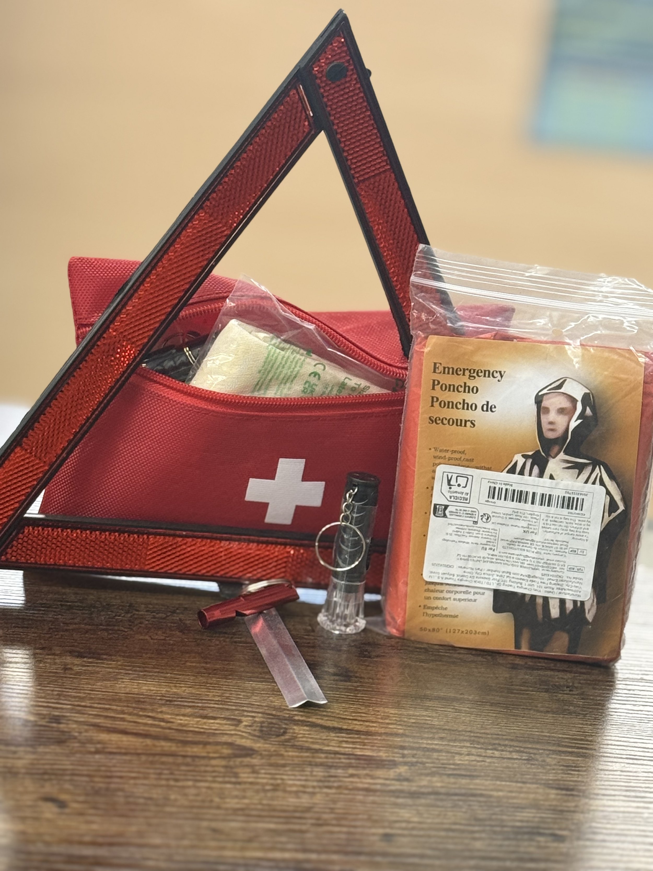 Emergency kit with a red first aid bag, reflective triangle, flashlight, whistle, and emergency poncho.