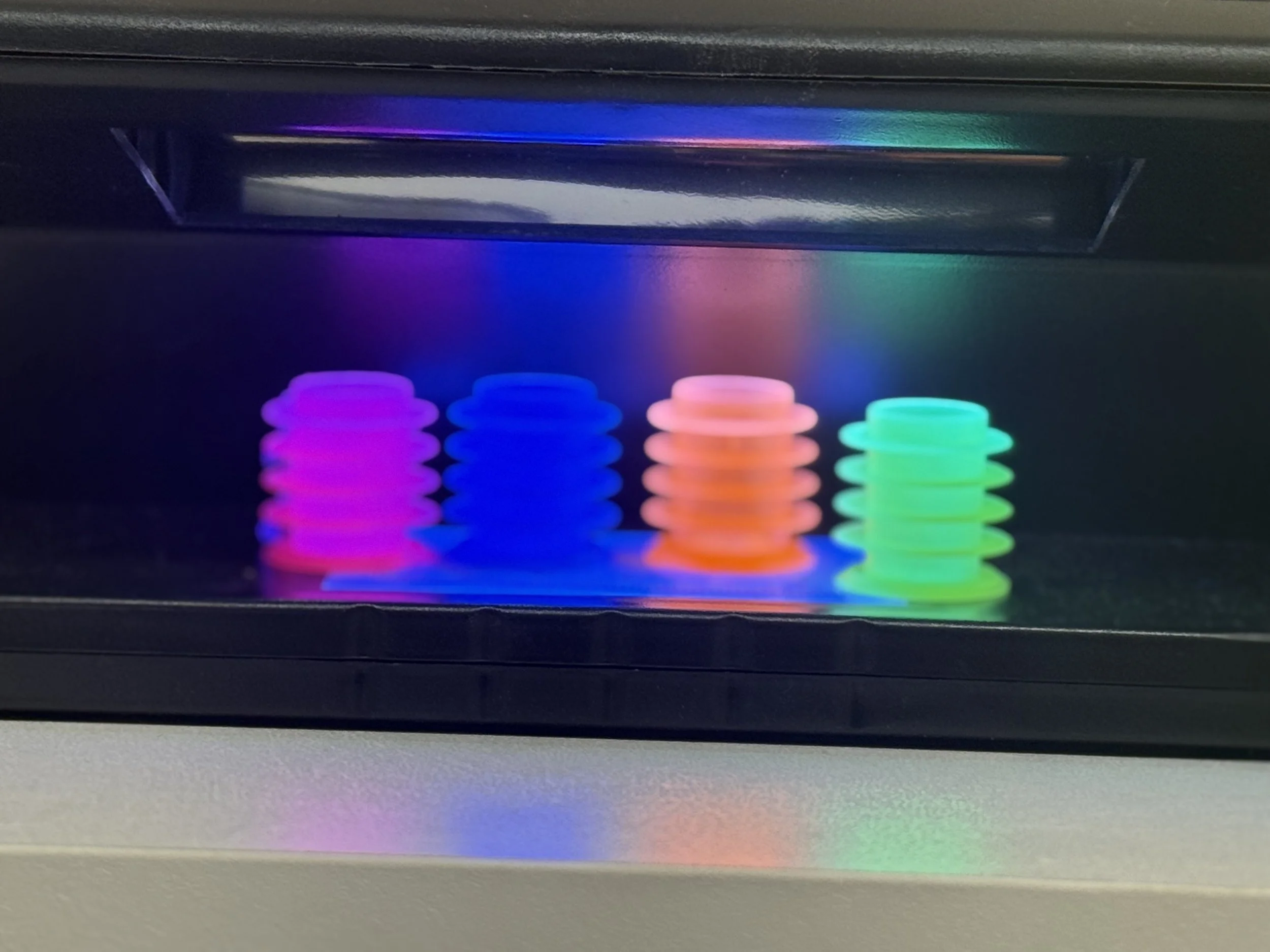 Colorful glow-in-the-dark springs in pink, blue, orange, and green, illuminated against a dark background.