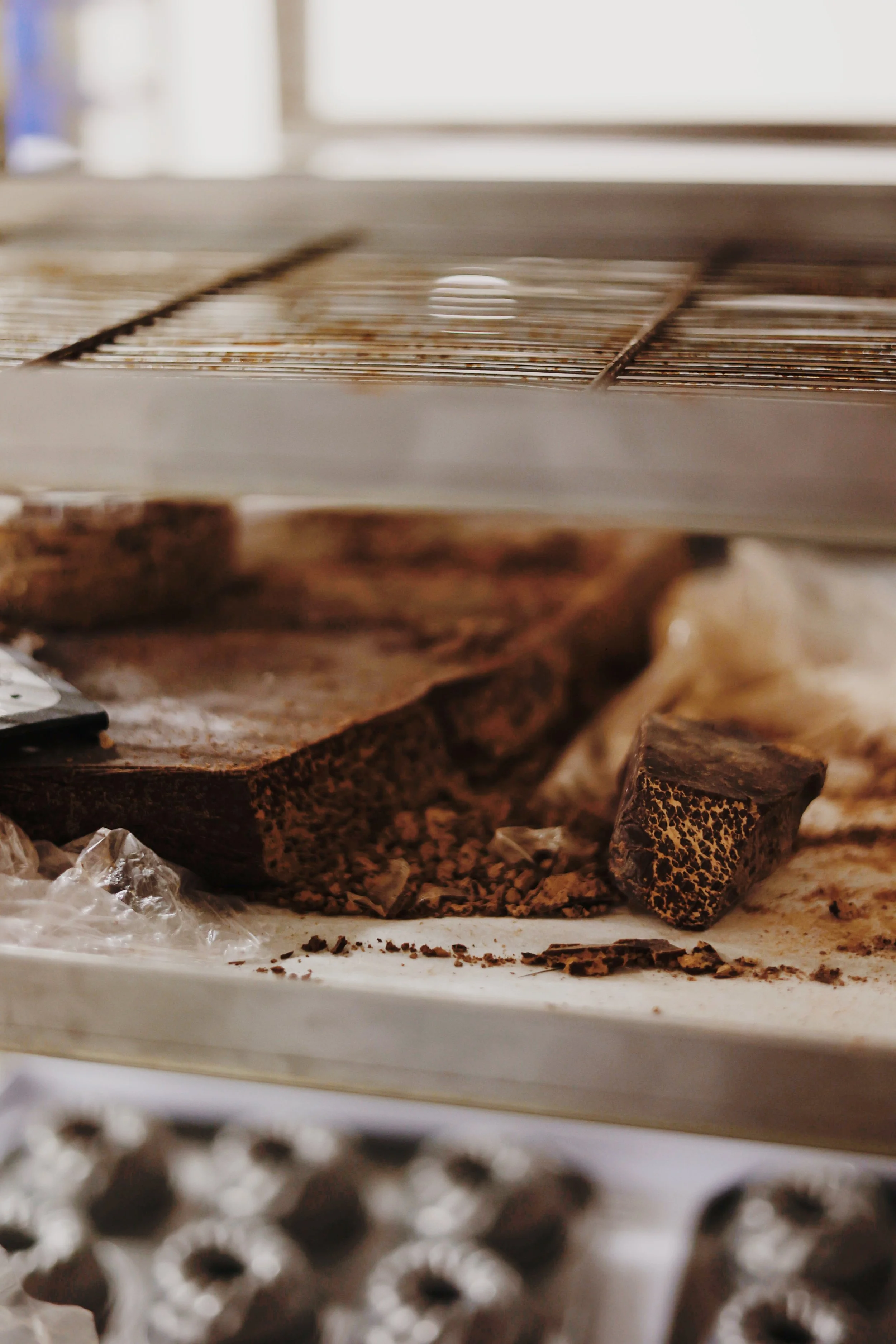 Close-up of a shelving unit with chocolate truffles and chocolate pieces, some broken, on the bottom shelf.