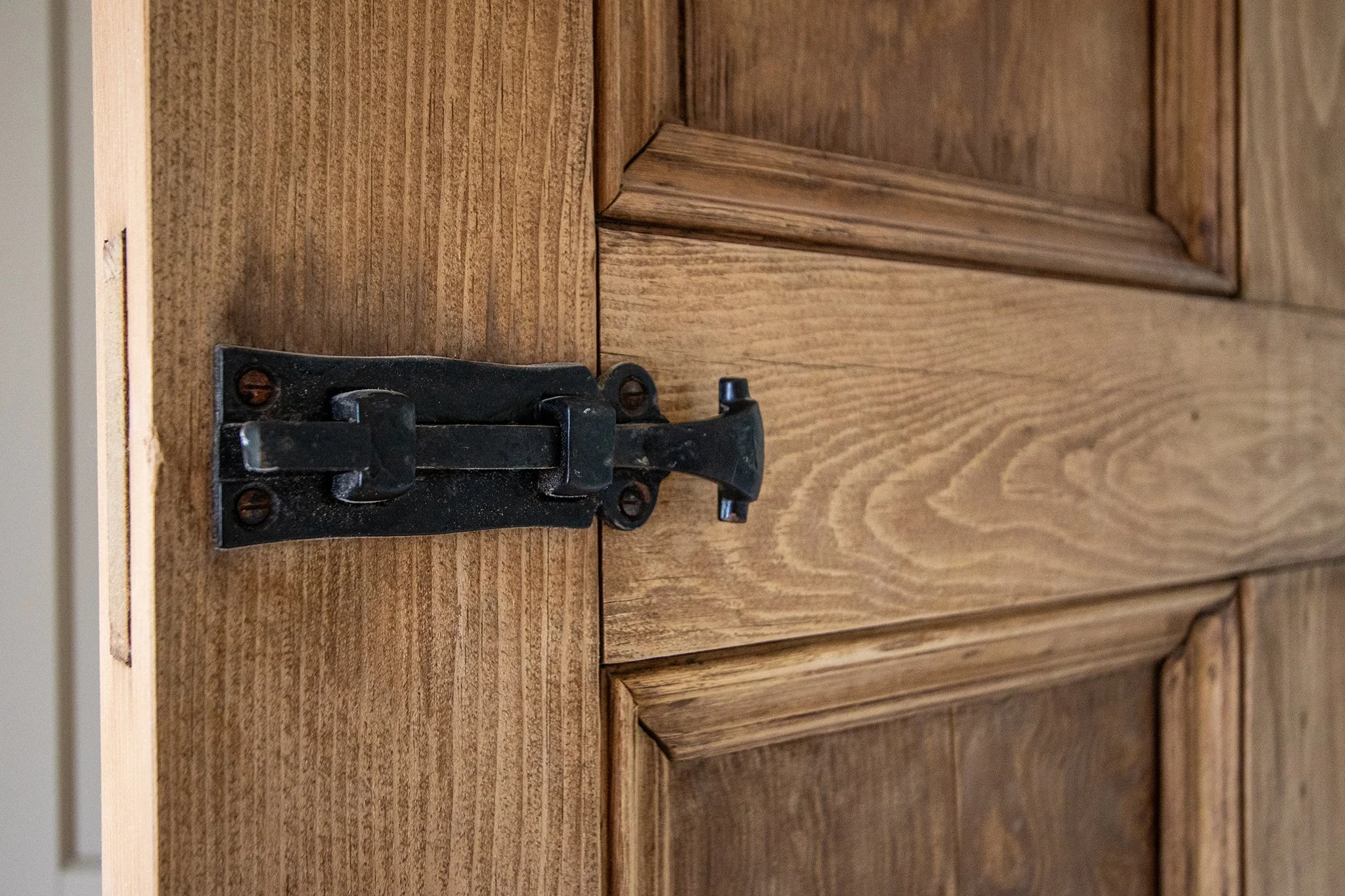 Close-up of a black door latch on a wooden door.