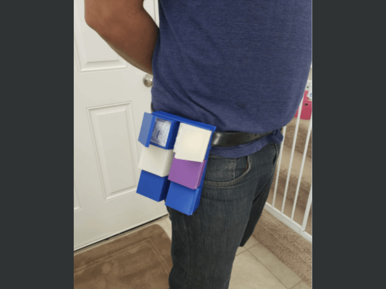 Person wearing a belt with colorful blocks attached, standing indoors near a door and staircase.