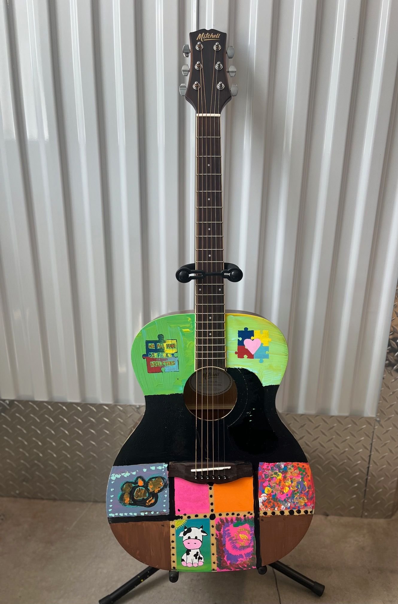 Decorated acoustic guitar with colorful artwork including puzzle pieces, animals, and abstract designs.