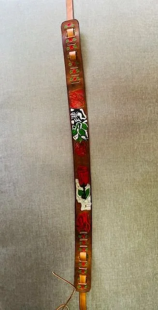 A vertical metal strip with holiday-themed decorations and cutouts, including a red bow, green holly with berries, and red ornaments, hanging against a beige wall.