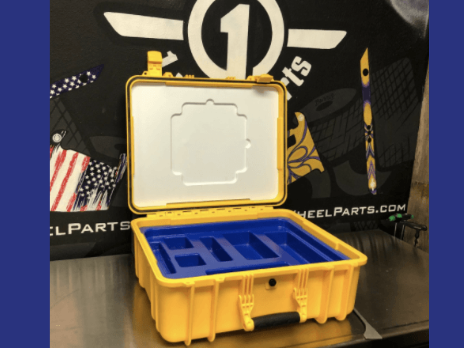 Yellow and blue plastic toolbox with compartments, open on a table, with a black and yellow handle.