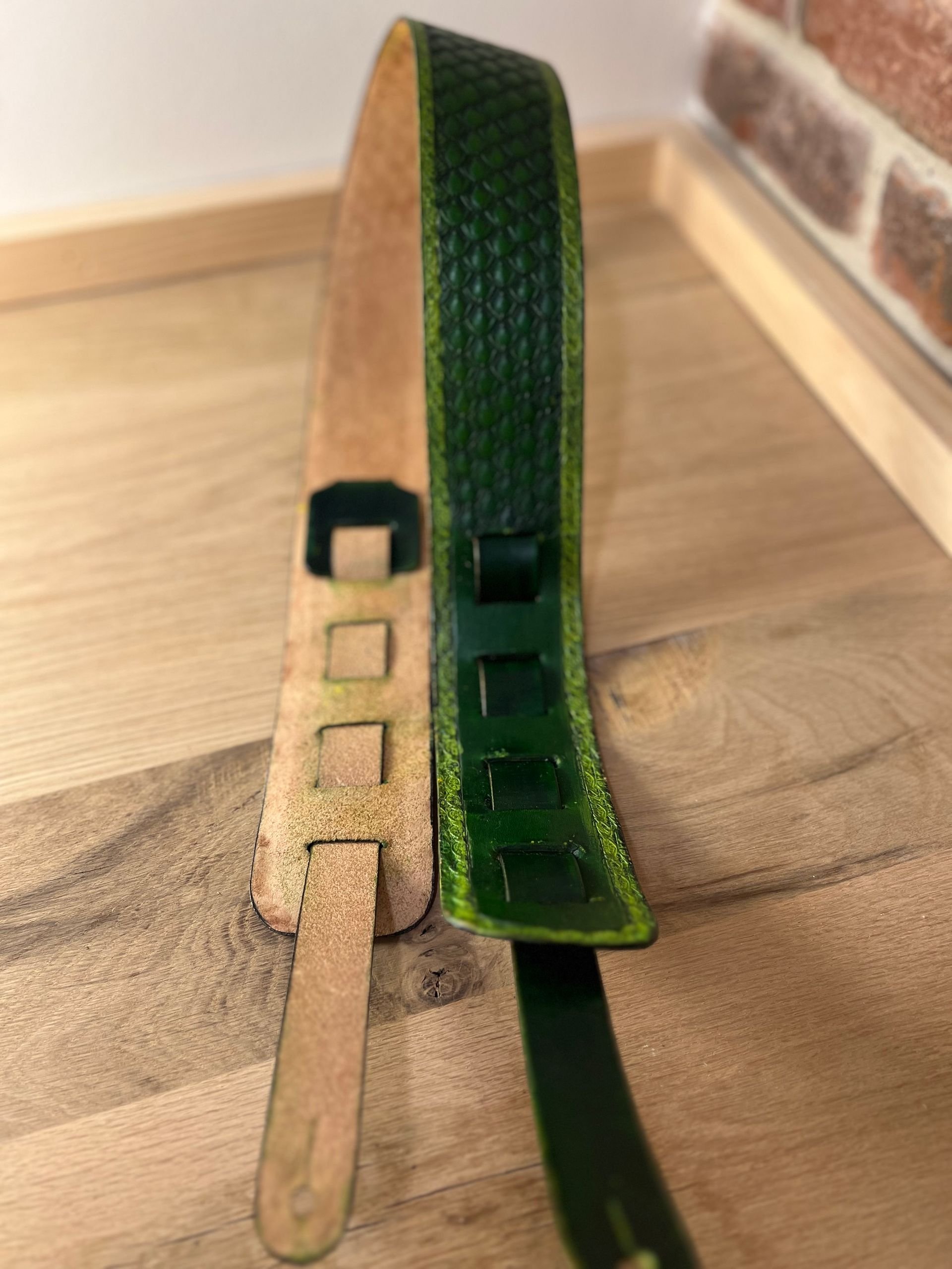 Two skateboard decks, one old and worn, the other new and green, placed on a wooden surface.
