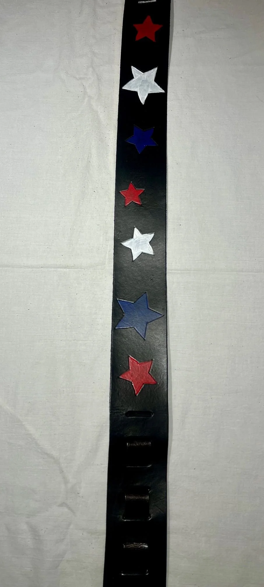 A black wristband decorated with alternating red, white, and blue stars.