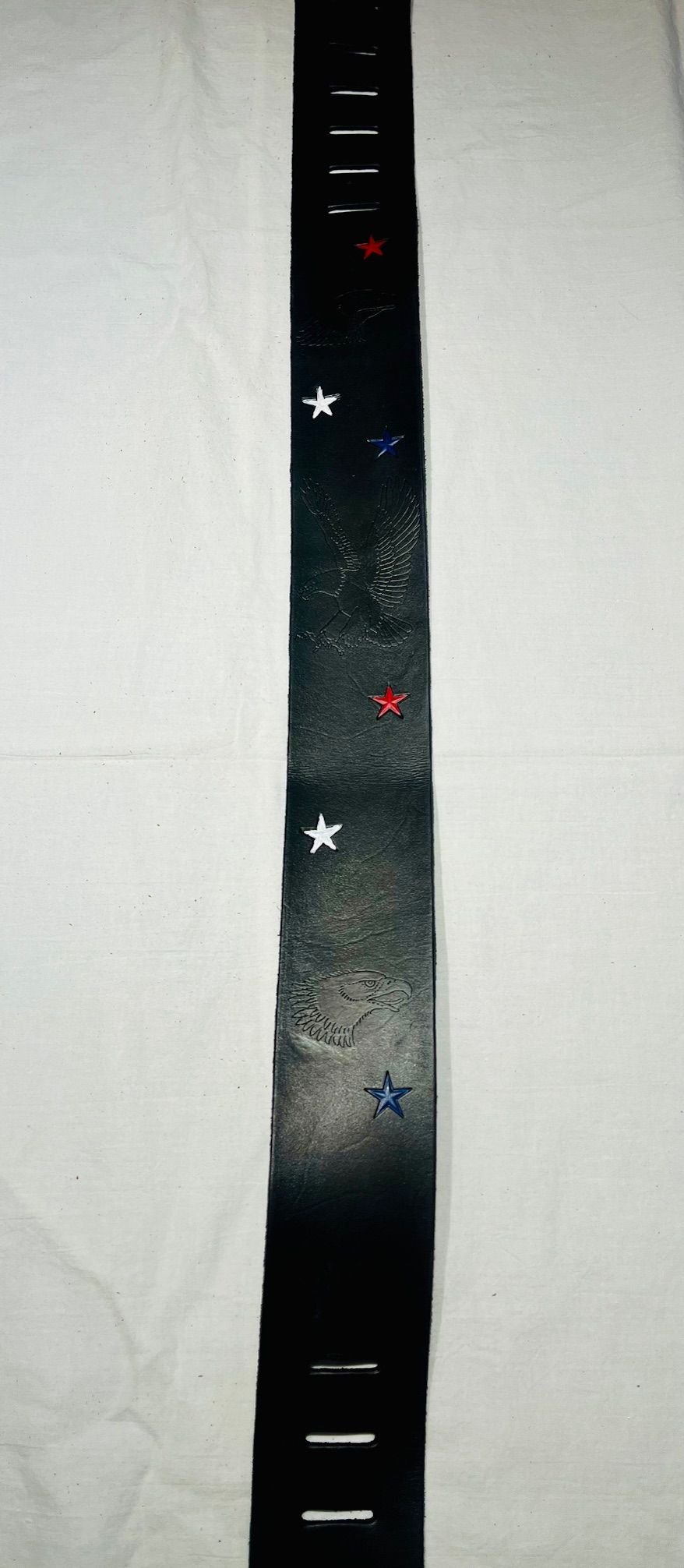 A black hockey belt with red, white, and blue stars, and a faint eagle emblem, laid flat on a white background.