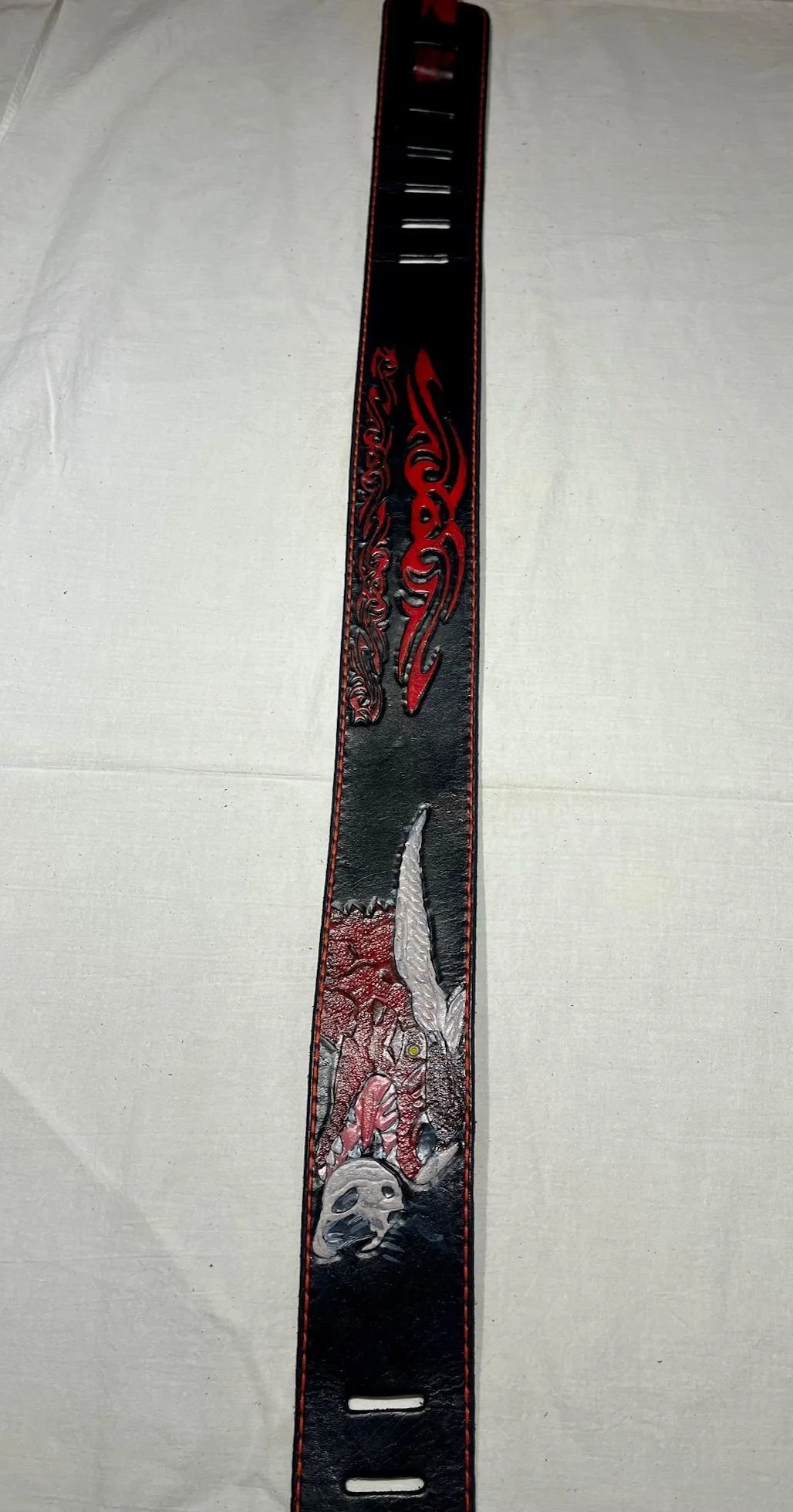 A black and red leather belt with intricate dragon and skull designs.