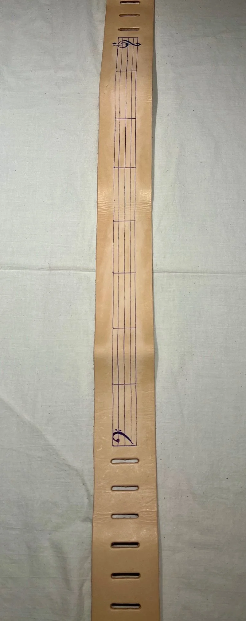 A wooden electronic musical instrument with six strings, resembling a small guitar or ukulele. It has fret slots and a decorative element near the top.
