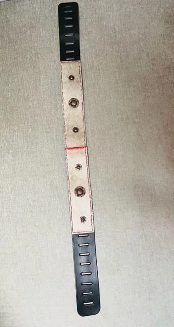 A wristband with a metal watch band clasp, placed on a gray surface.