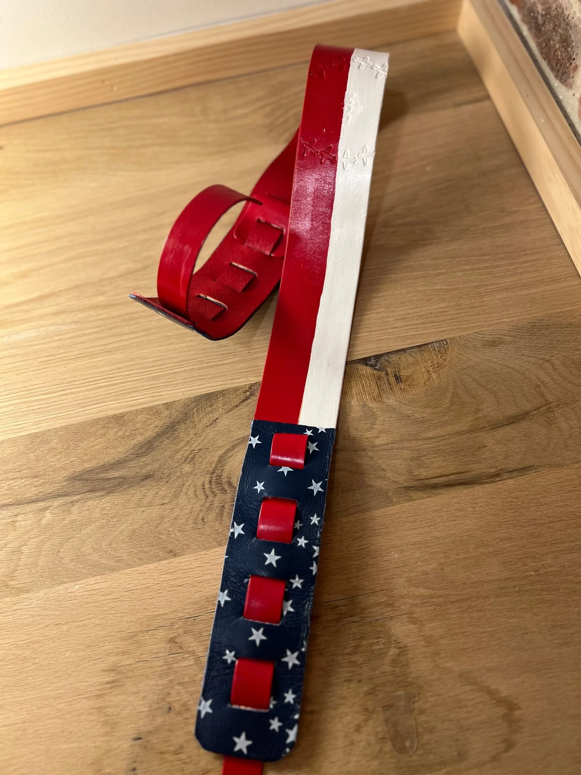 A decorative belt painted with an American flag design, featuring red, white, and blue colors with stars.