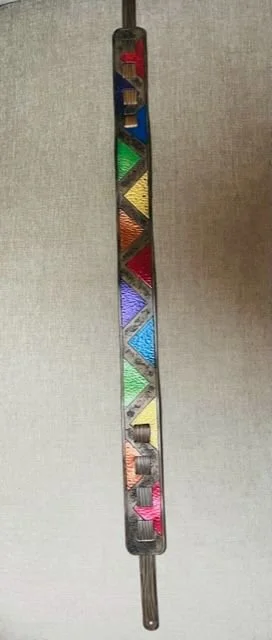 A metal box with colored sections inside, holding various small tools or objects, and a metal handle extending from the bottom.