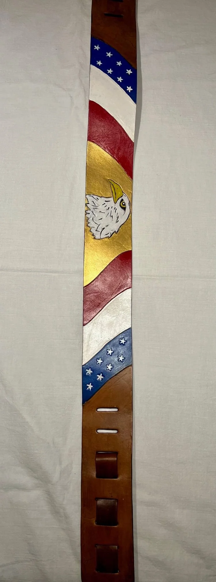 A leather belt with painted American patriotic theme, featuring an eagle head and stars.