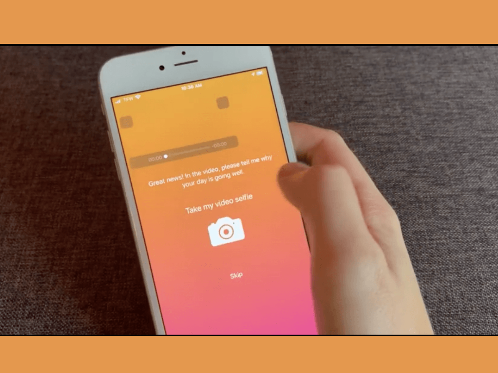 A person holding a smartphone with the screen displaying instructions to take a selfie video, with a gradient orange and pink background.