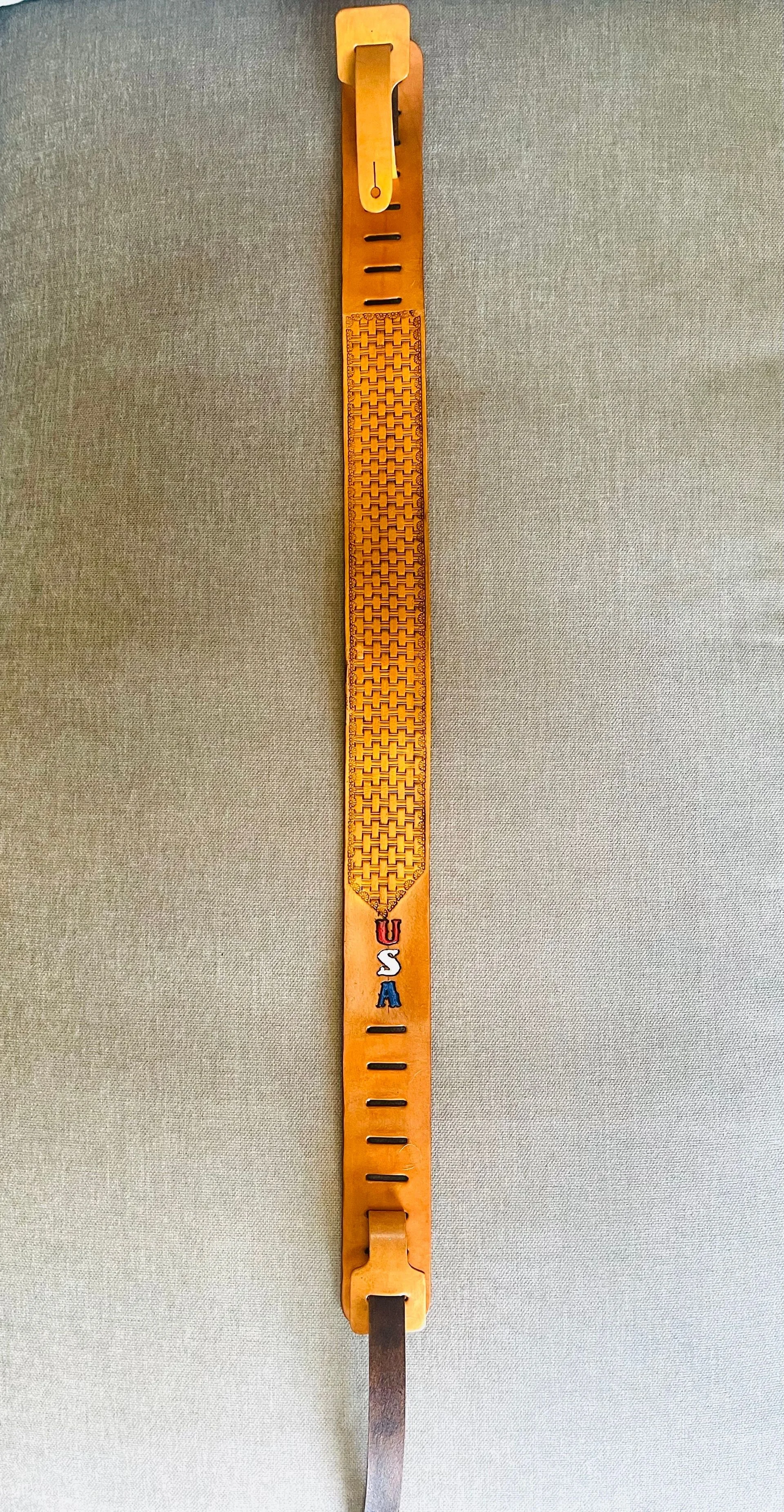 A vintage wooden golf club measurement stick with the letters 'USA' painted on it, mounted vertically on a gray wall.