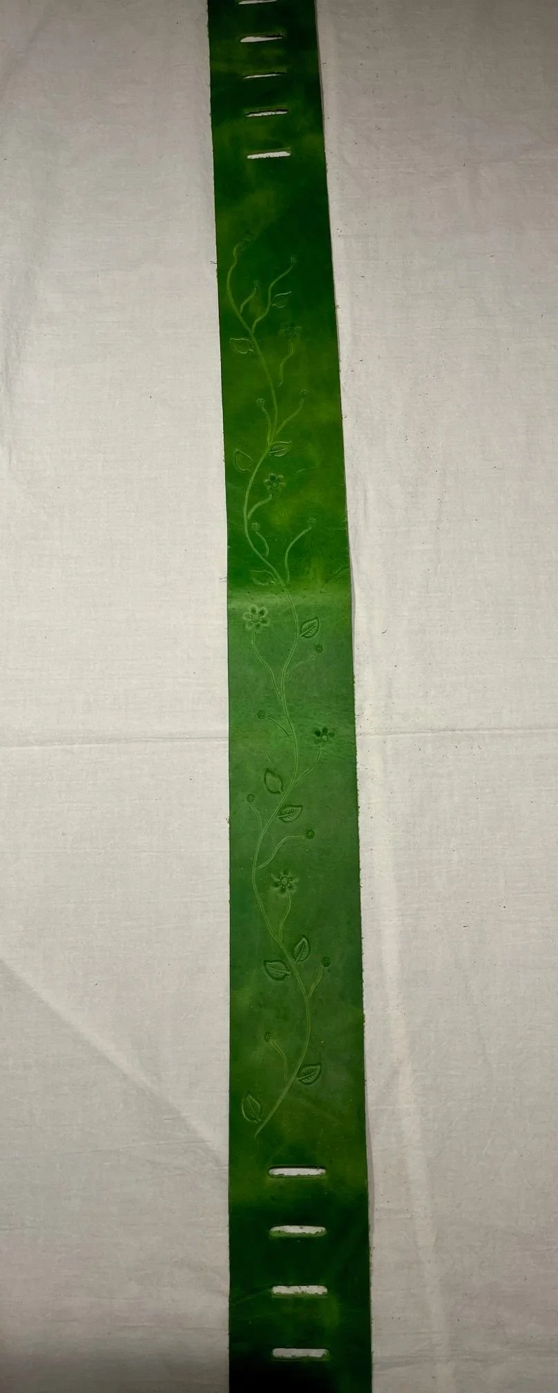 Green ruler with floral and leaf patterns, placed on a white surface.