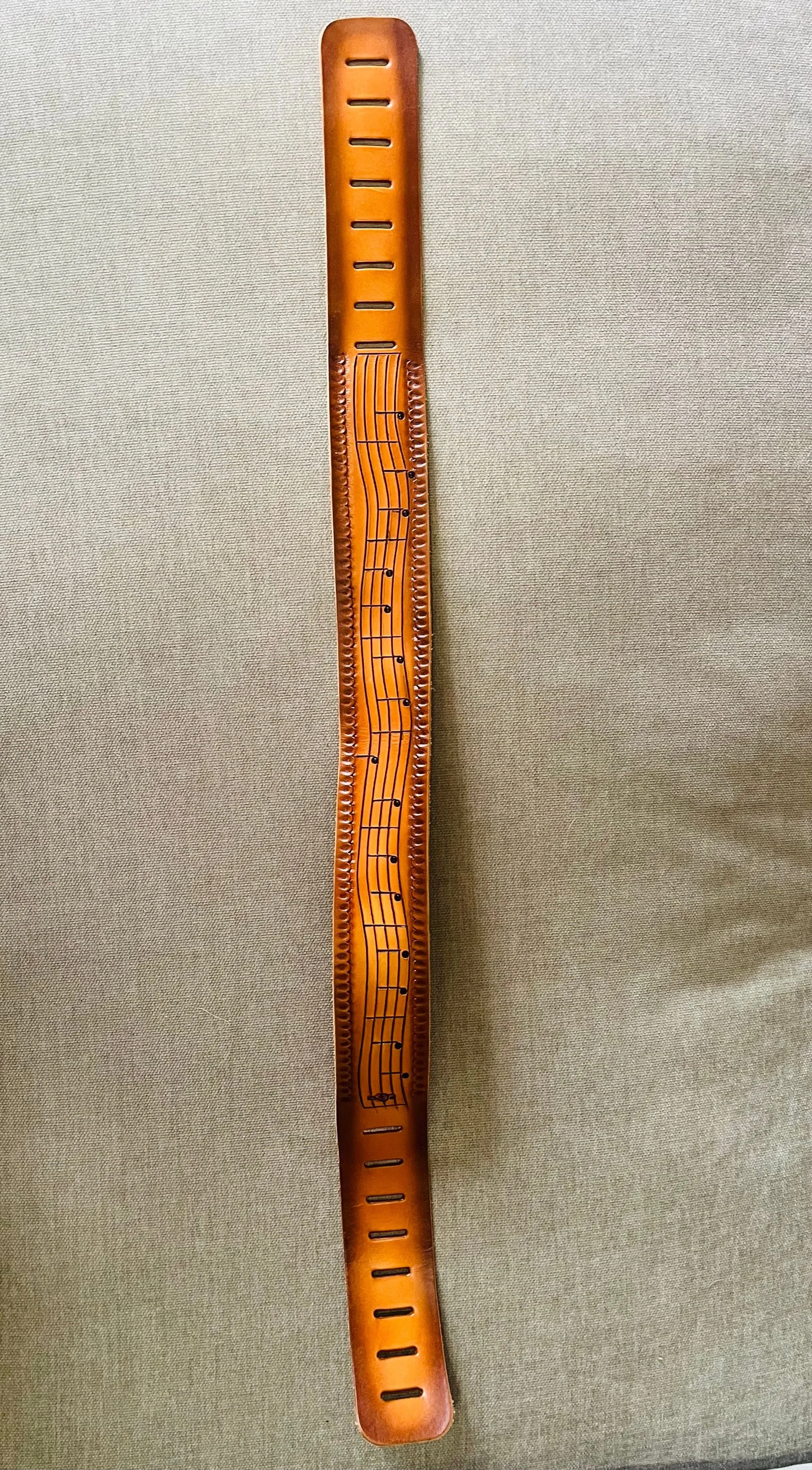 Orange plastic ruler with musical staff and notes printed on it, lying on a beige fabric surface.