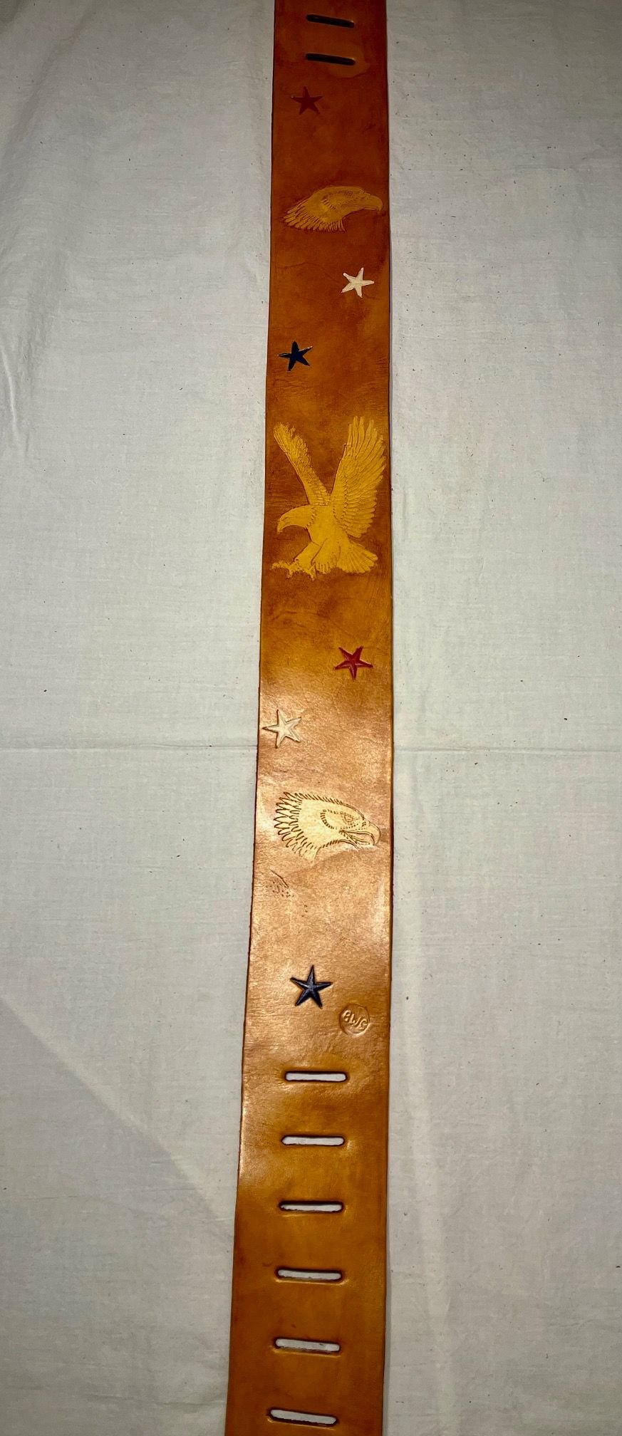A leather strap with etched eagle and star designs, featuring a reddish-brown color.