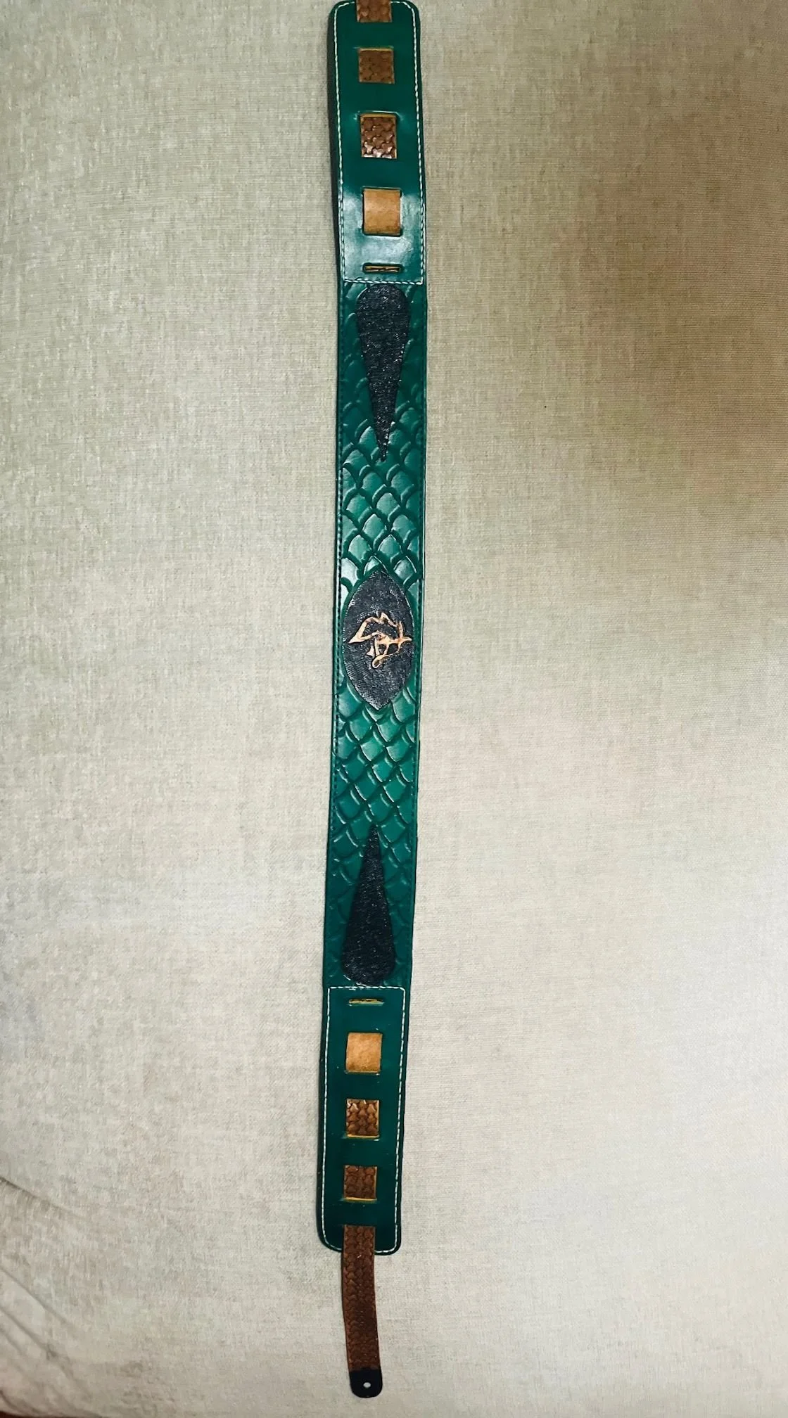 A teal and brown leather watch strap with black and gold decorative details.
