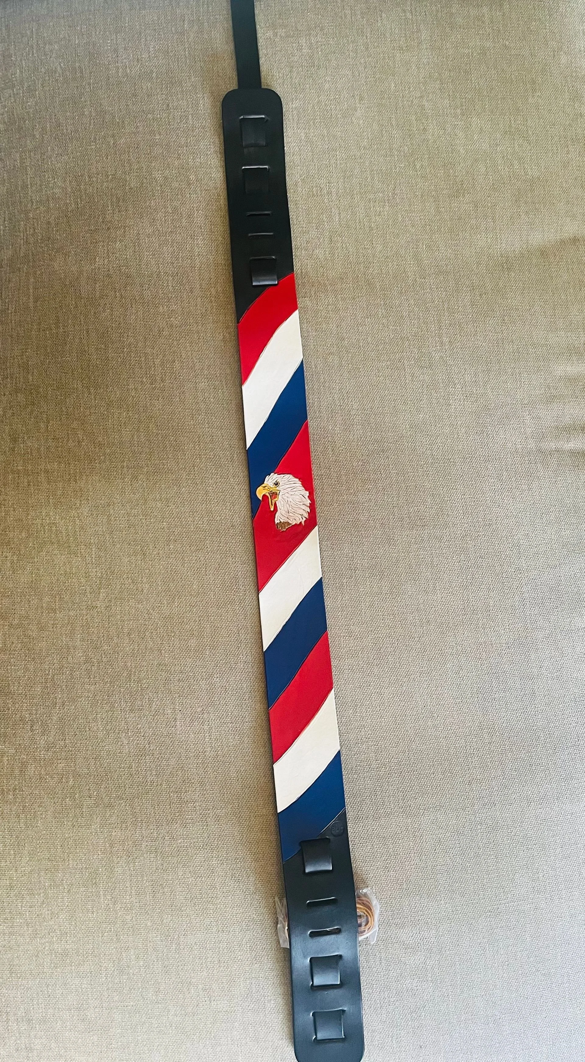 Barber's barber pole with red, white, and blue stripes and an eagle head emblem.