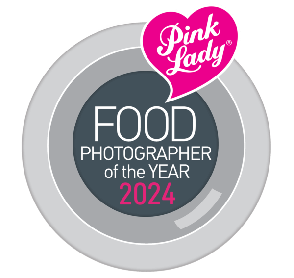 Pink Lady Food Photographer of the Year 2024 award logo, featuring a circular design with gray and white shades and the Pink Lady brand pink heart logo at the top.