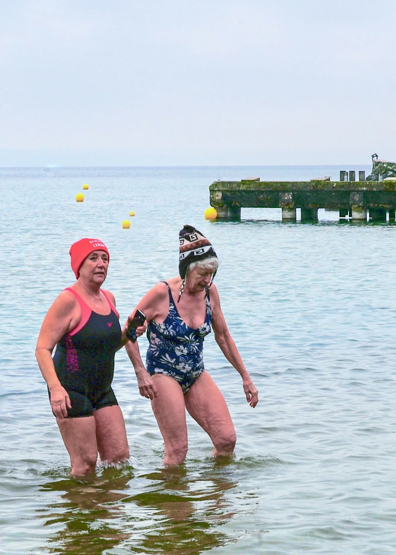two women swimming in hats in  winter in lake geneva catherinelewisphotography.jpg