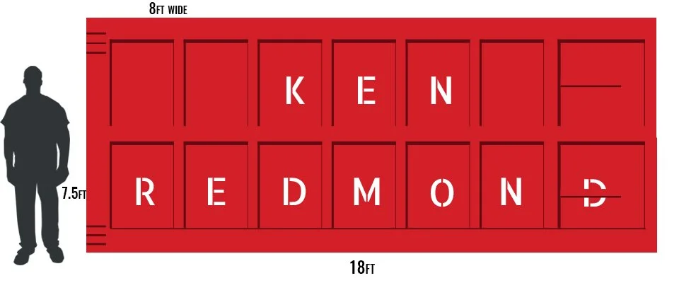 A red rectangular yard sign with black text showing the address 'KEN REDMOND' in large blocked letters. The sign measures 8 feet wide, 7.5 feet tall, and 18 feet long, with a black silhouette of a person standing for scale.