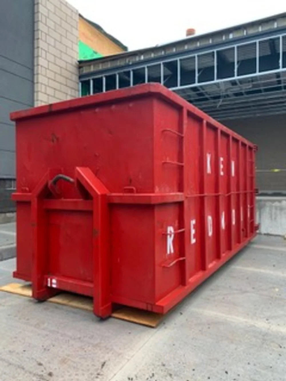 A large red dumpster placed outdoors on wooden pallets.