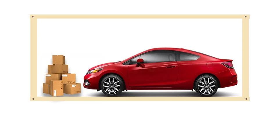 Red sedan car parked next to a stack of cardboard boxes.