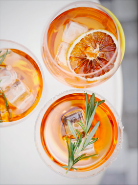 Three glasses of iced tea with lemon slices and herbs, viewed from above.