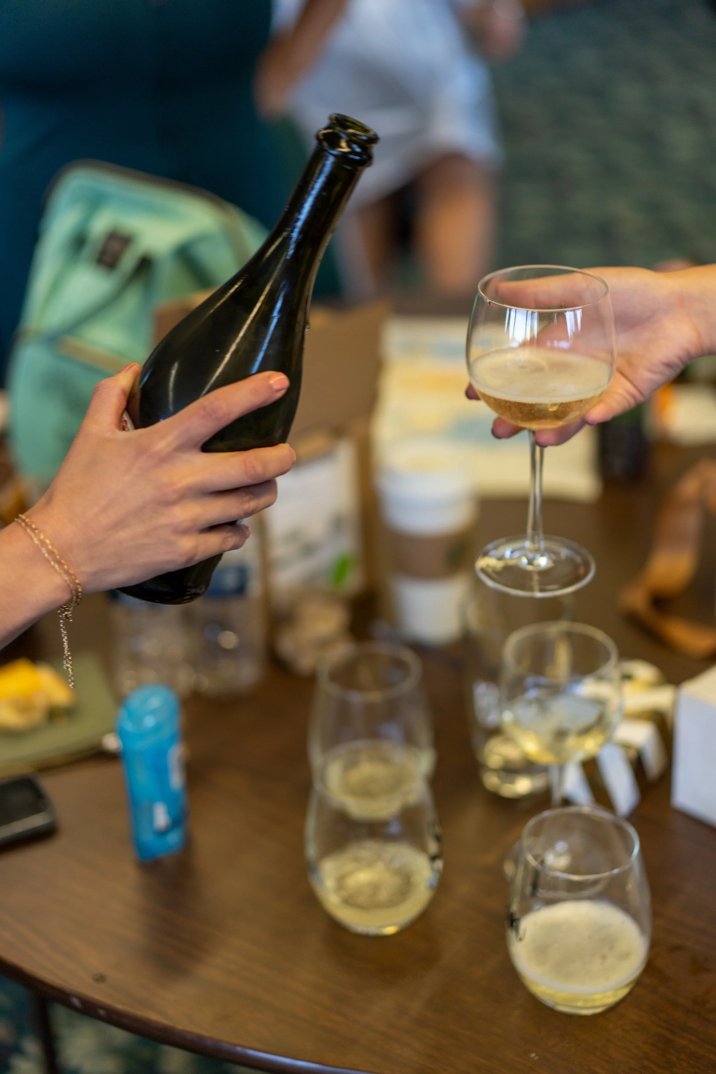 People pouring and serving glasses of champagne at a social gathering.