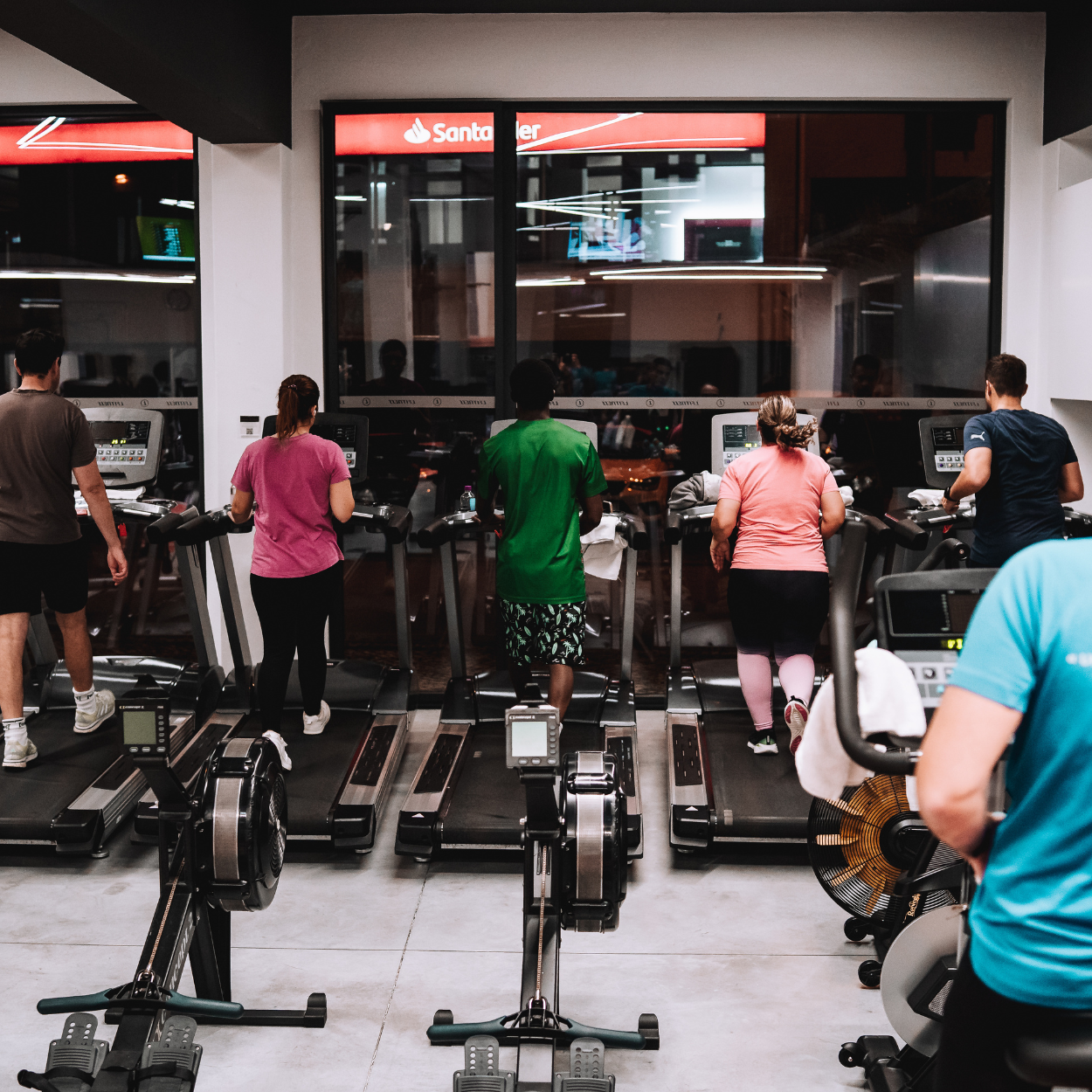 Pessoa usando esteira no interior de academia de ginástica à noite.