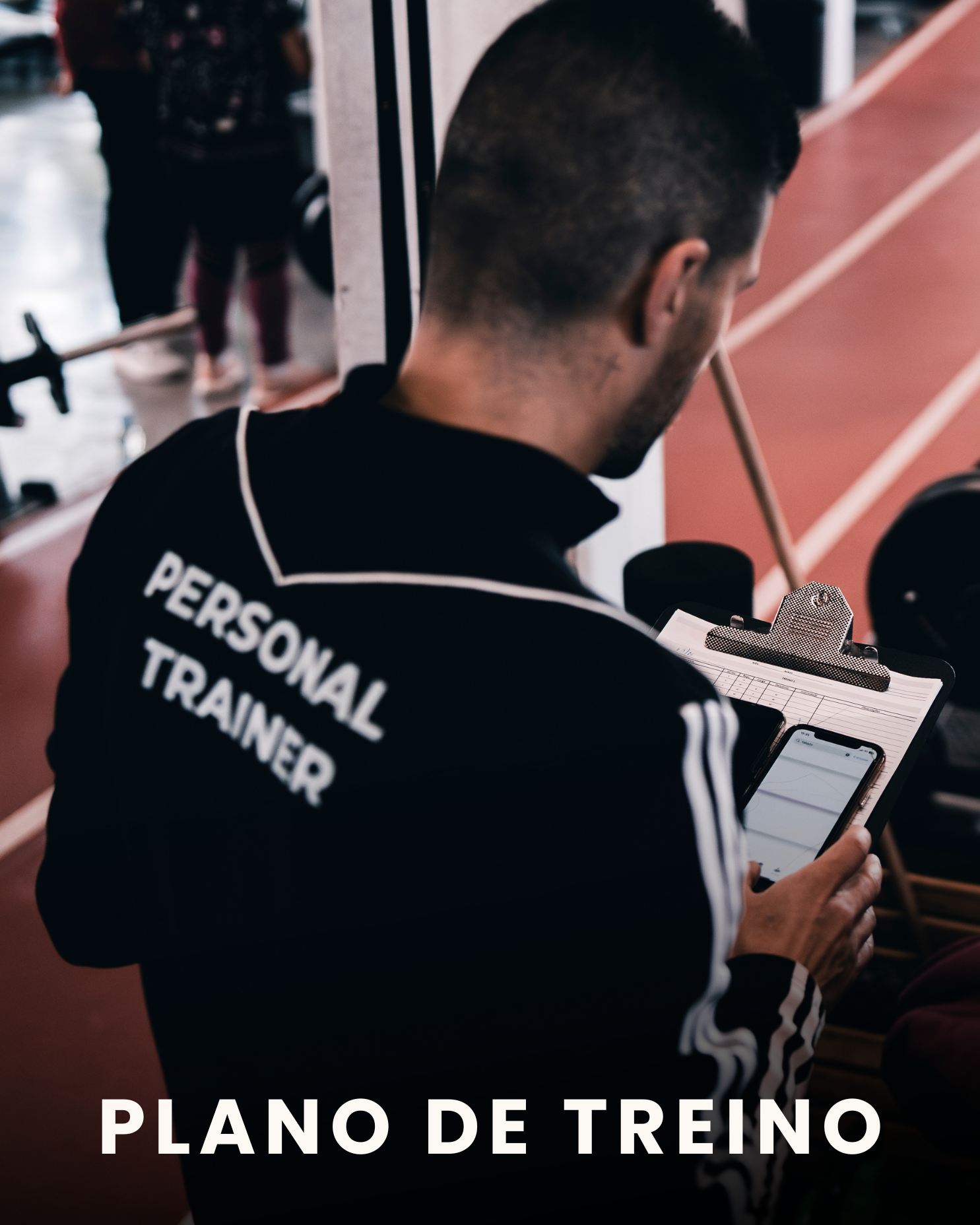 Pessoa com roupa de treinador pessoal, observando dados em um tablet e telefone, em uma academia de ginástica.