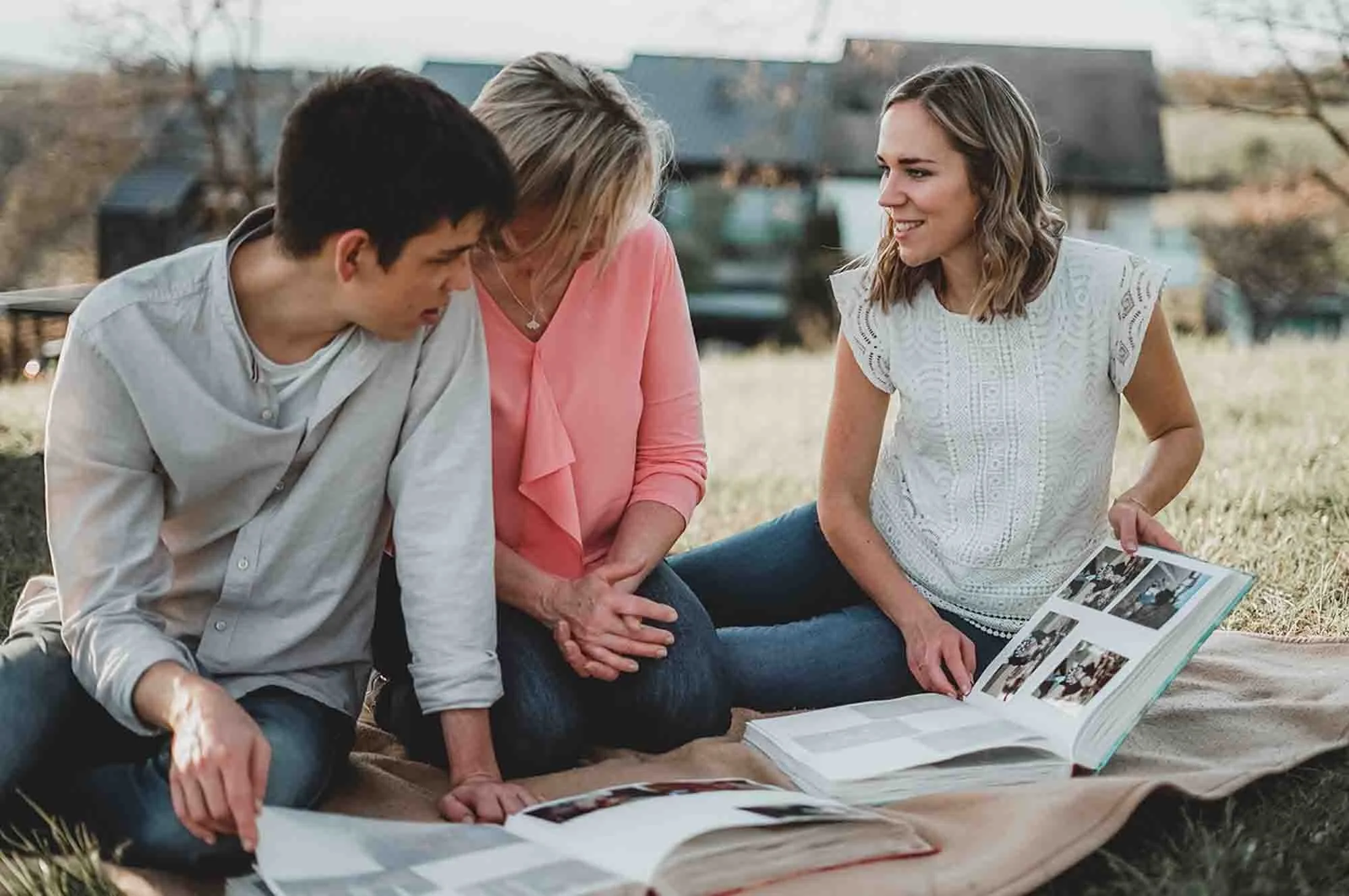Eine Familie sitzt auf einer Decke im Freien und schauen gemeinsam in ein Fotobuch.