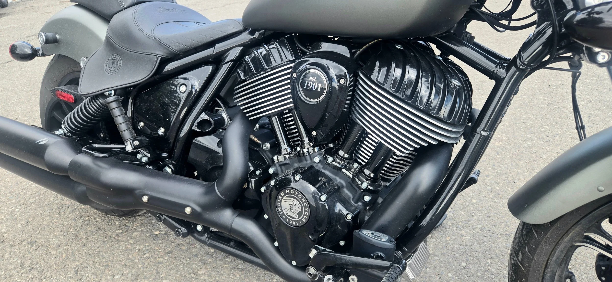 Close-up of a black motorcycle engine with chrome accents, displaying the text "est 1901" on the engine cover and a logo reading "Indian Motorcycle 1901".